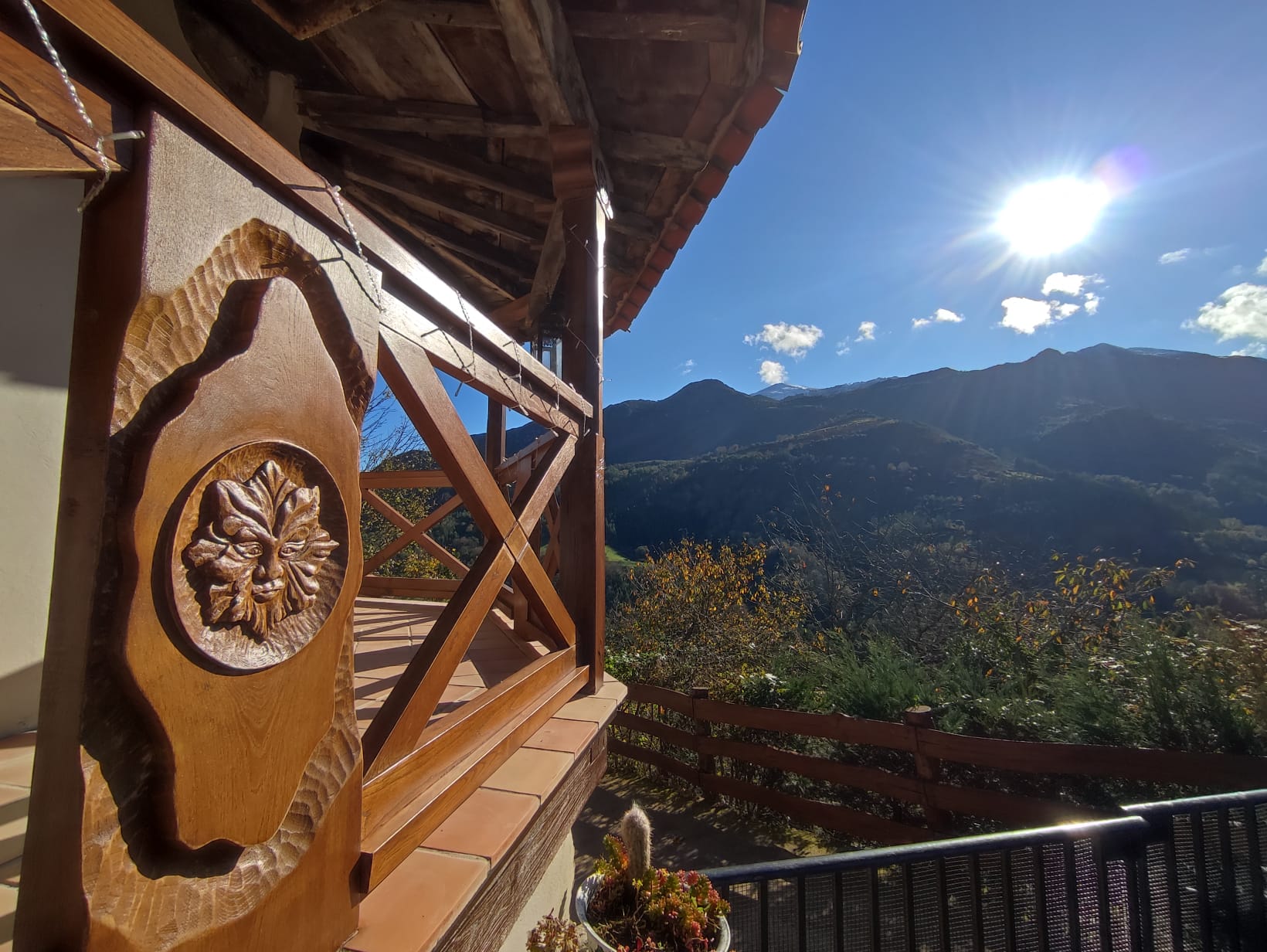 Balcón con roseta tallada en madera y vistas a montañas asturianas
