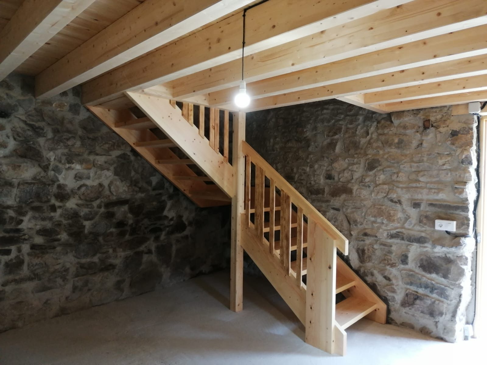 Escalera de madera maciza con muro de piedra
