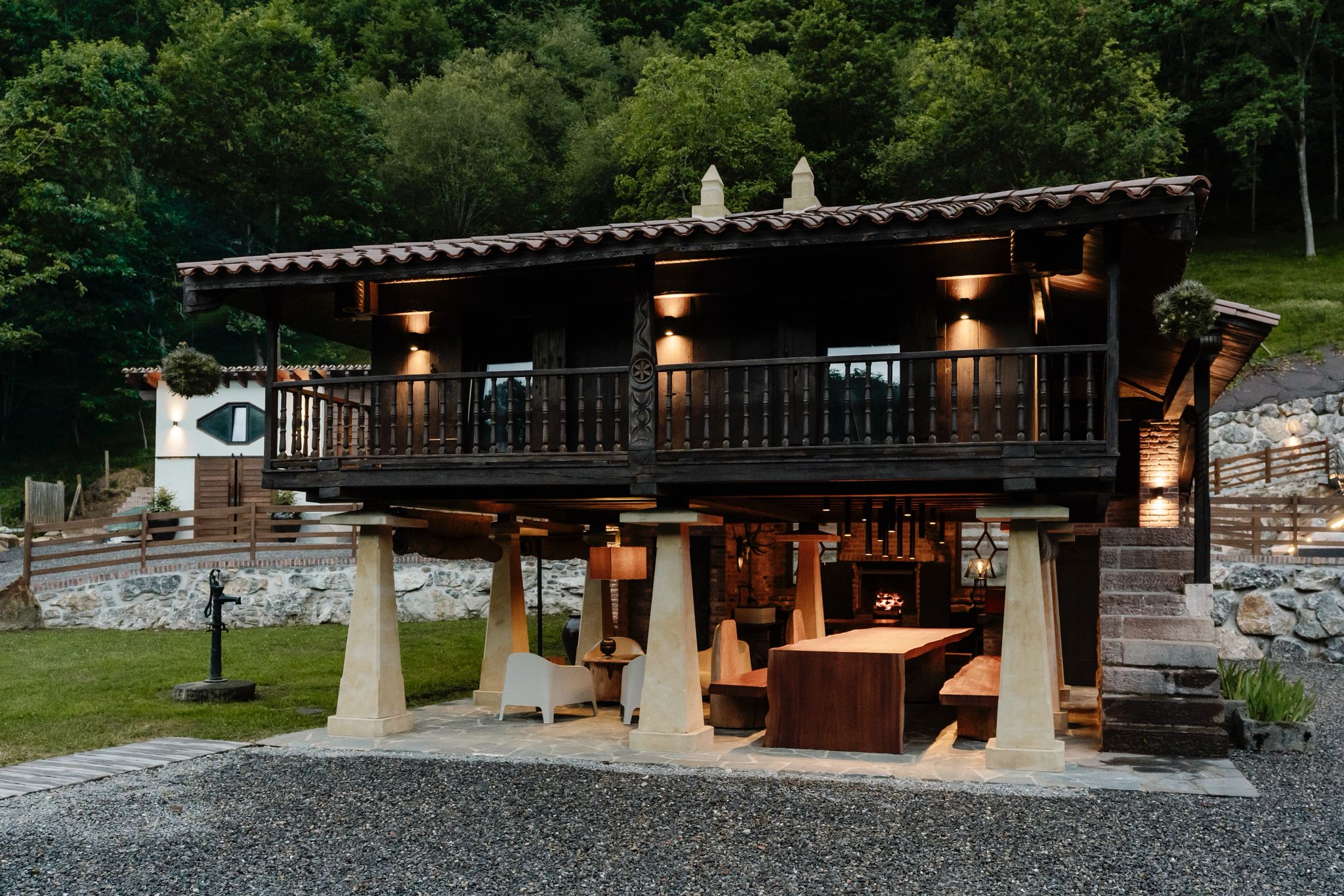 Hórreo asturiano restaurado con iluminación nocturna y mesa de madera maciza