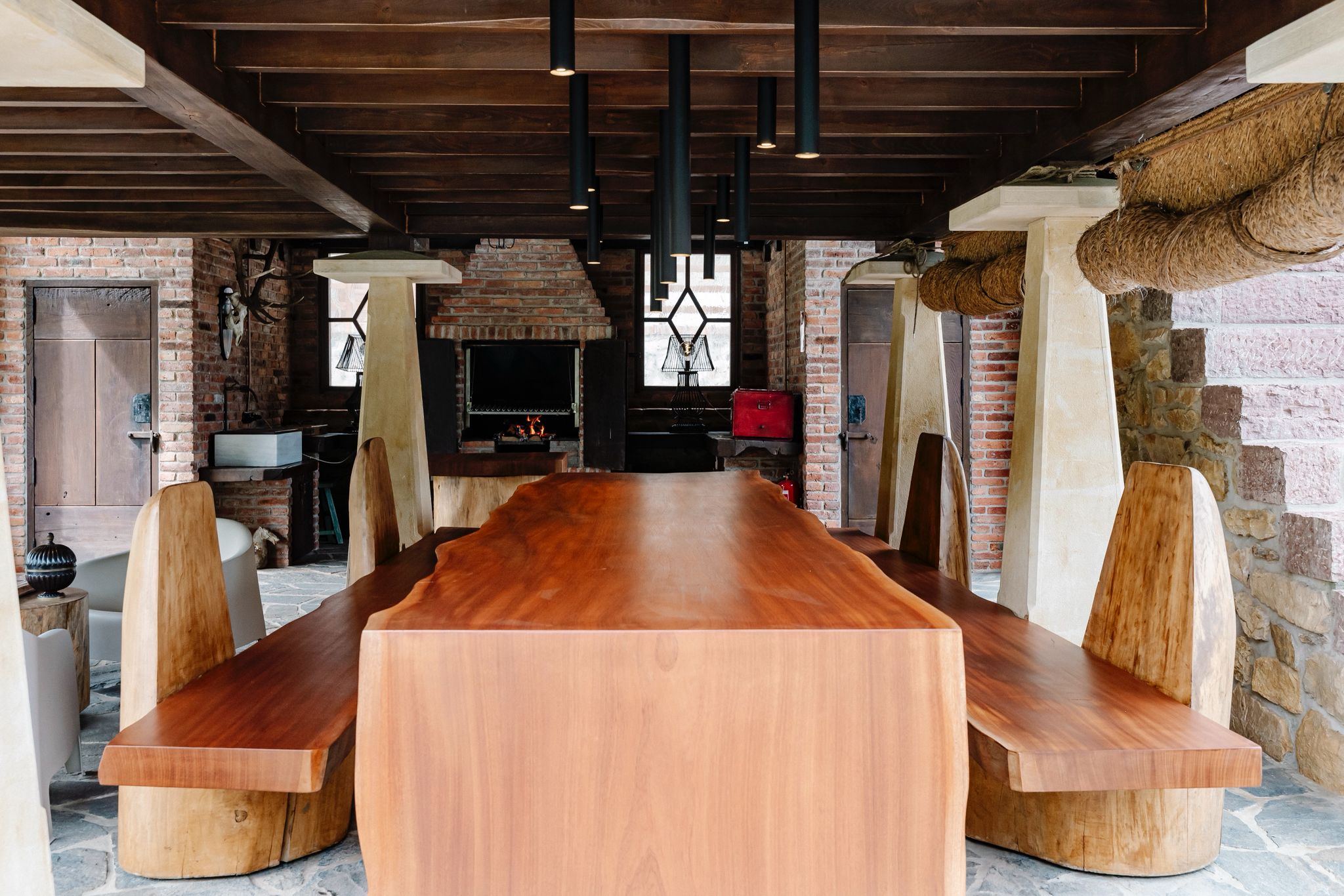 Mesa monolítica de madera maciza con sillas artesanales en salón rústico